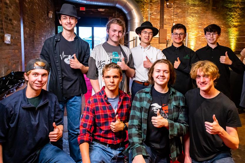 A group of young men smiles and gives a thumbs up